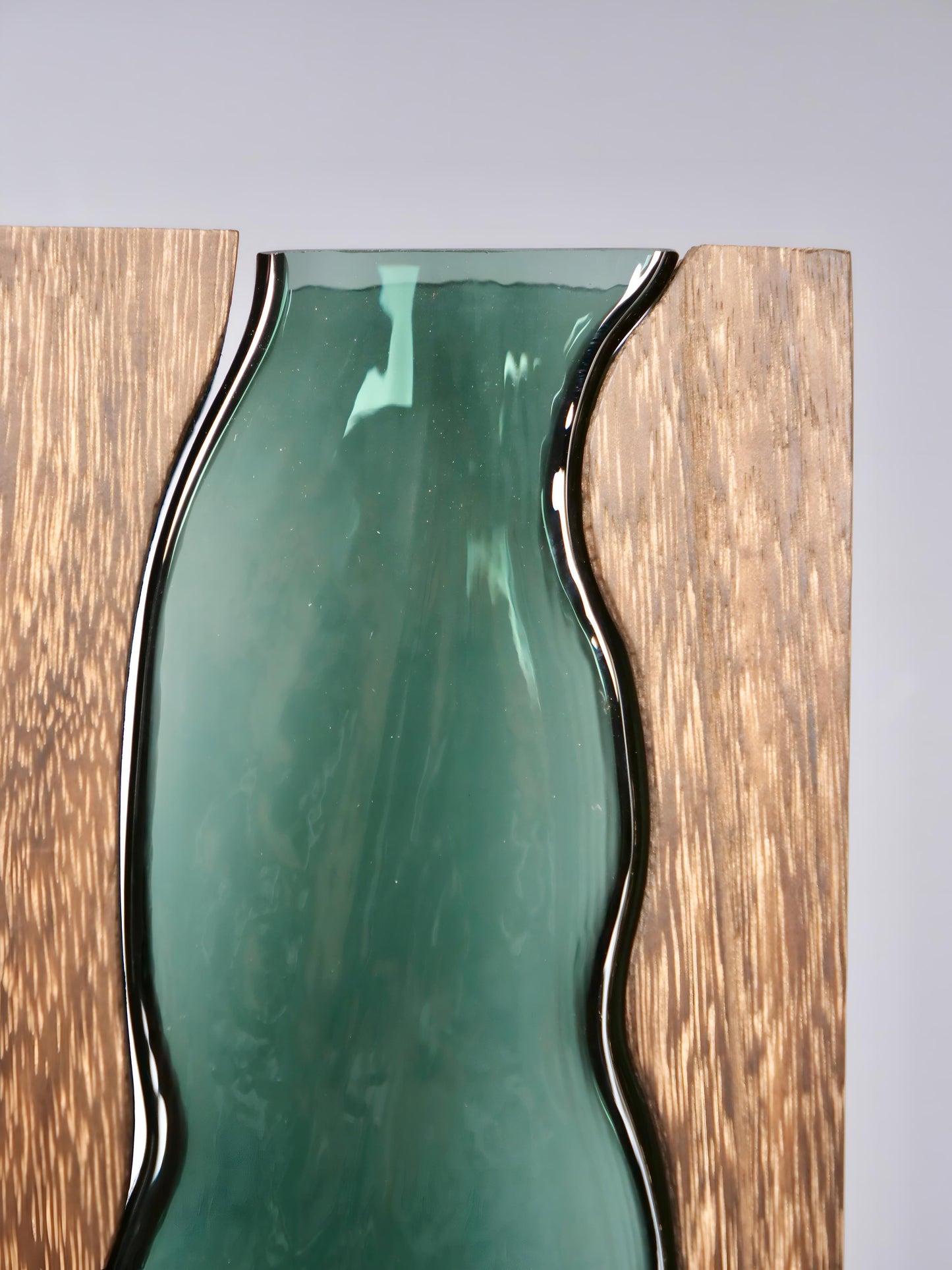 a green vase sitting on top of a wooden shelf